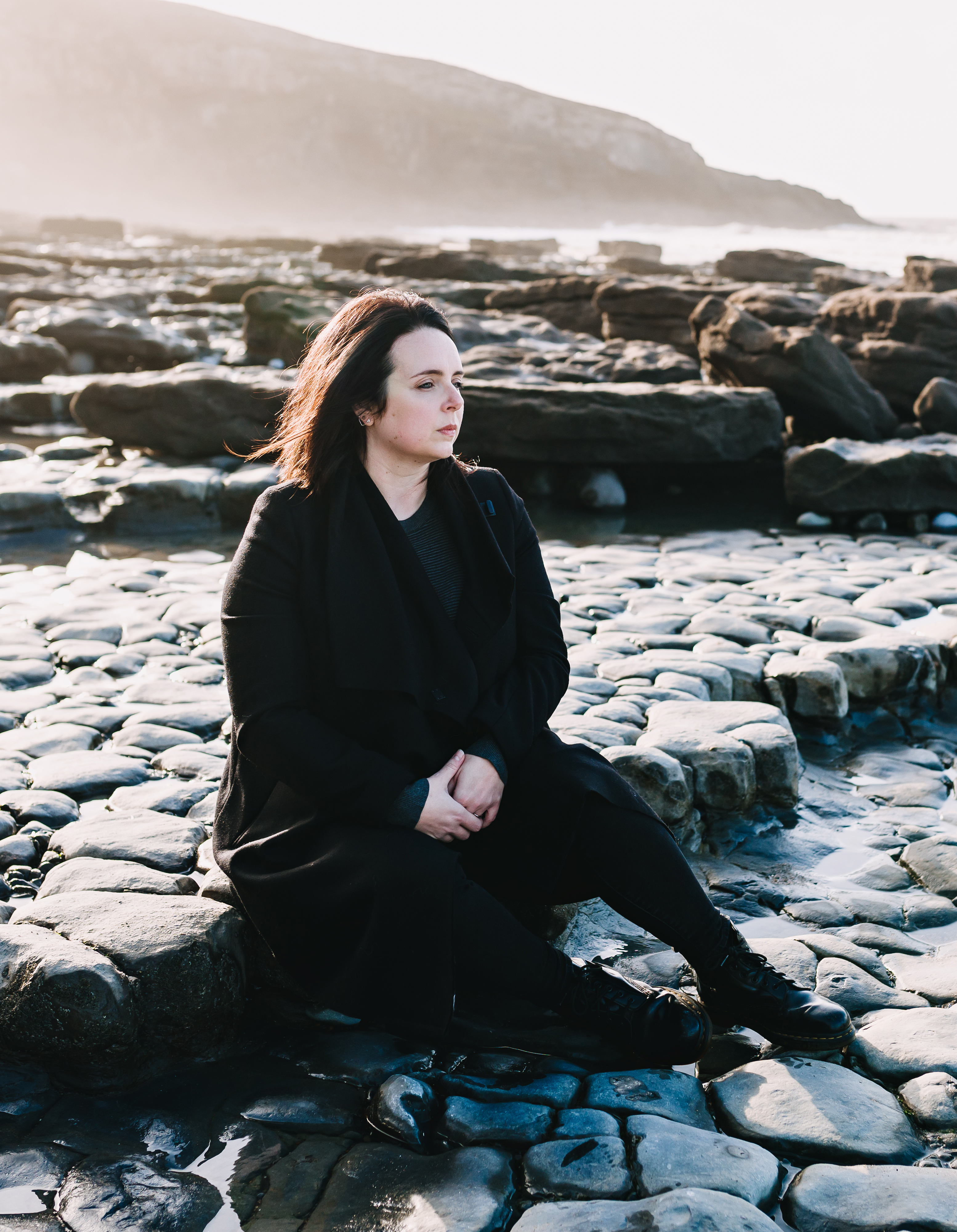 A colour photo of Sophie Keetch sitting on a rock.